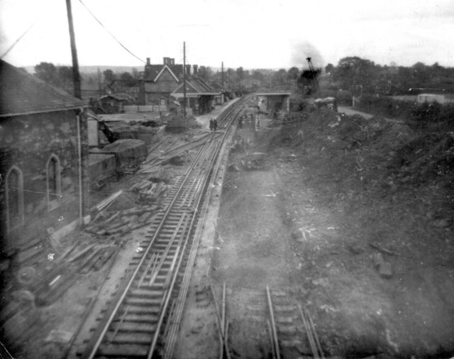 Remodelling of track layout through Charfield - photo taken I think in summer 1956. The pointwork from the goods shed turntable leading to the up (right-hand) main line has been all but removed and new track laid on the down (left-hand) side. The old asbestos Bibby animal feed shed is still in place - this was soon to be replaced by a concrete warehouse. The trackbed under up main line through the station platform has been excavated in readiness for re-ballasting and new track. The goods shed stands today as it did then. :  : 